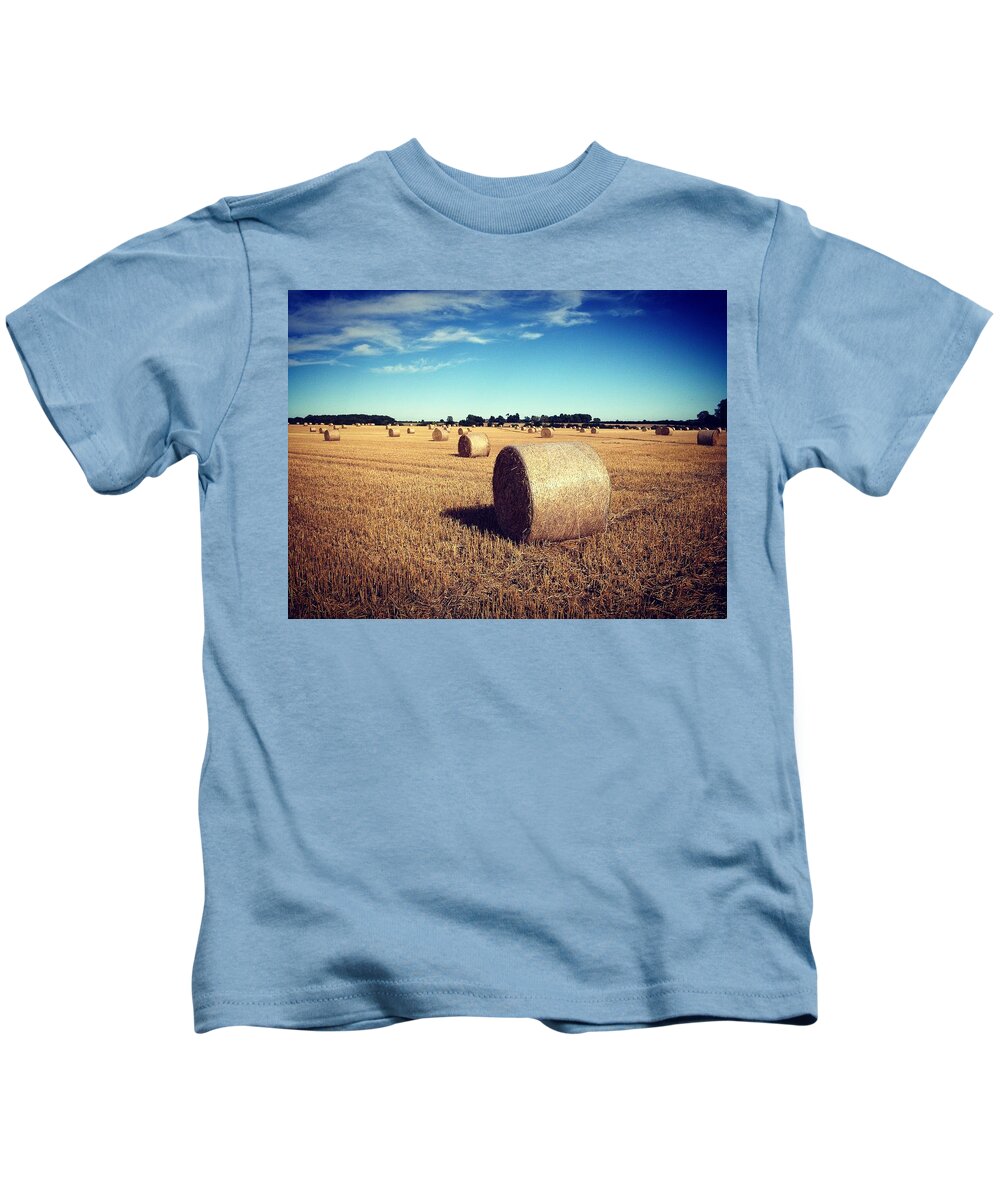 Areas Kids T-Shirt featuring the photograph Straw bales at harvest time #1 by Seeables Visual Arts