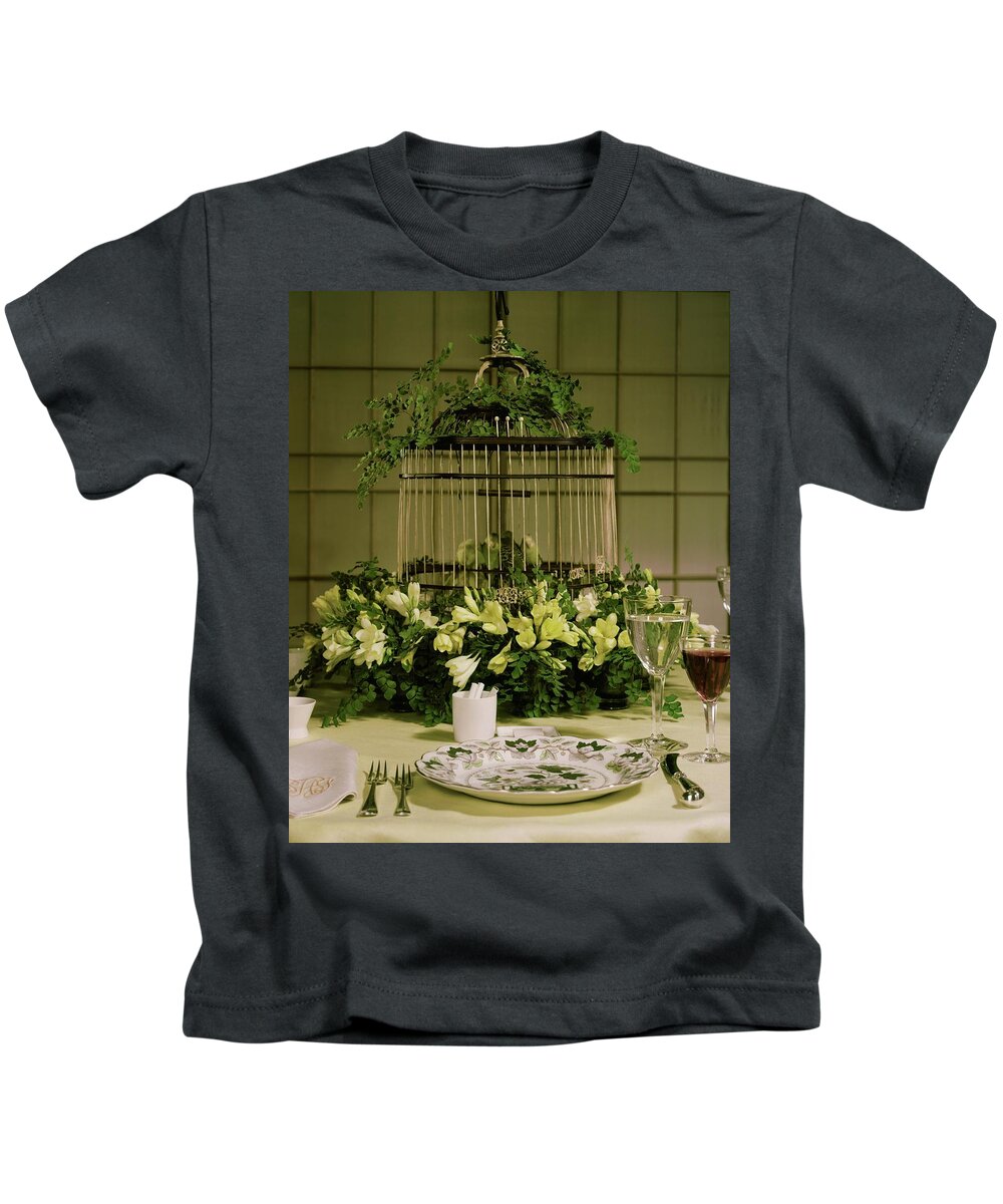 Studio Shot Kids T-Shirt featuring the photograph A Birdcage In The Middle Of A Table by Wiliam Grigsby