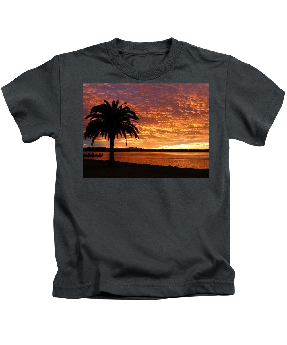 Australia Background Beautiful Beauty Cloud Clouds Evening Foreground Gold Hastings Holiday Horizon Jetty Landscape Leaf Leaves Macquarie Nsw Ocean Orange Palm Paradise Port Purple Red Reflects Relax River Romantic Sea Silhouette Silhouetted Sky Summer Sun Sunny Sunset Travel Tree Tropical Vacation Wake Water Weather Kids T-Shirt featuring the photograph Palm Tree Sunset by Fraser McCulloch