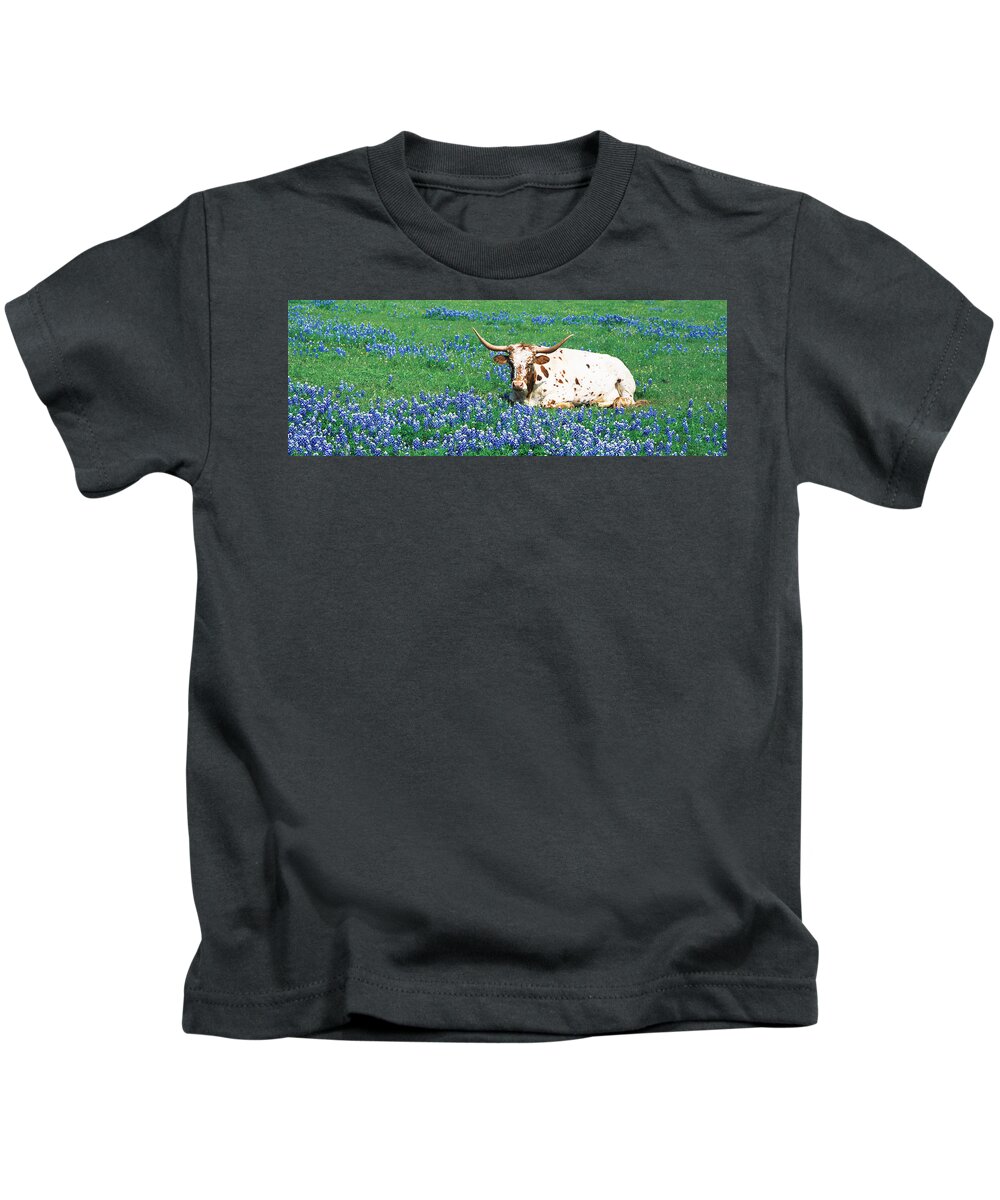 Photography Kids T-Shirt featuring the photograph Texas Longhorn Cow Sitting On A Field by Panoramic Images