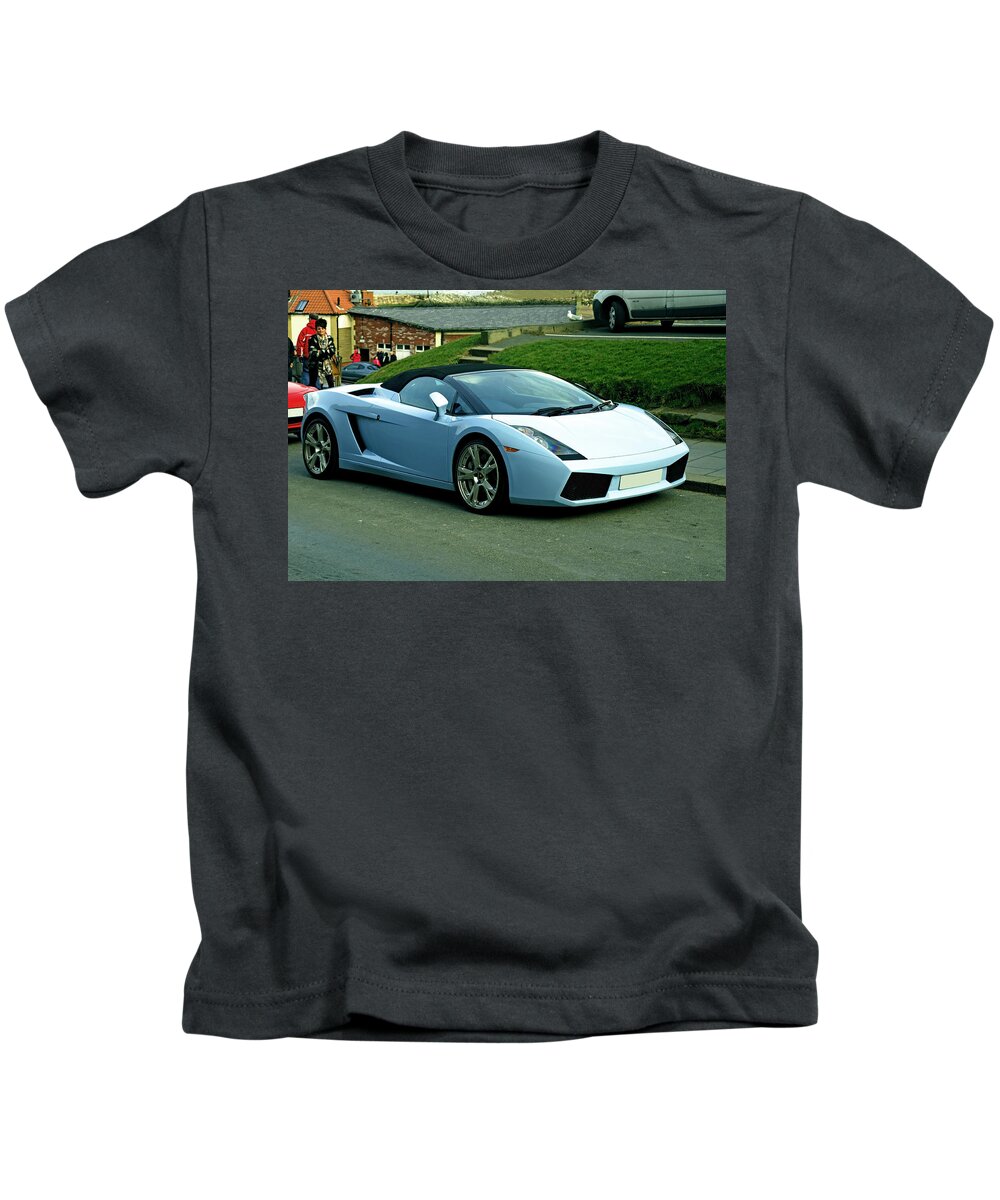 Britain; England; Uk; United Kingdom; Europe; North Yorkshire; Whitby; Buildings; People; Road; Cars; Car; Motor Cars; Passers-by; Sports Car; Luxury; Convertible; Coupe; Two-door; Roadside; Bright; Outdoors; Spring; Horizontal; Light Blue Kids T-Shirt featuring the photograph Luxury Sports Car - Whitby by Rod Johnson