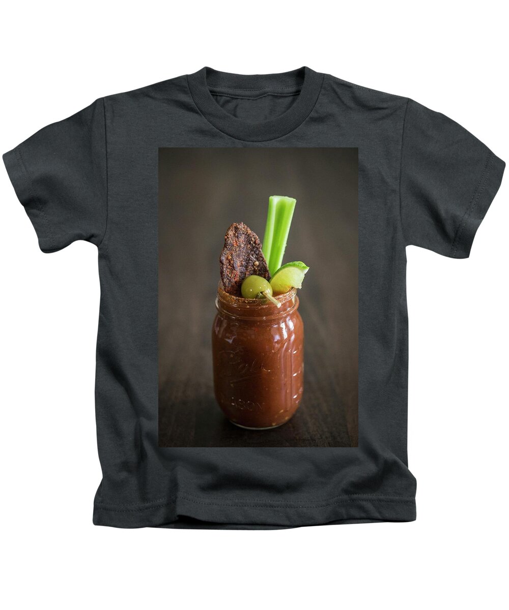 Ip_11376780 Kids T-Shirt featuring the photograph A Bloody Mary With Beef Jerky, An Olive, Lime And A Stick Of Celery by Julia Cawley