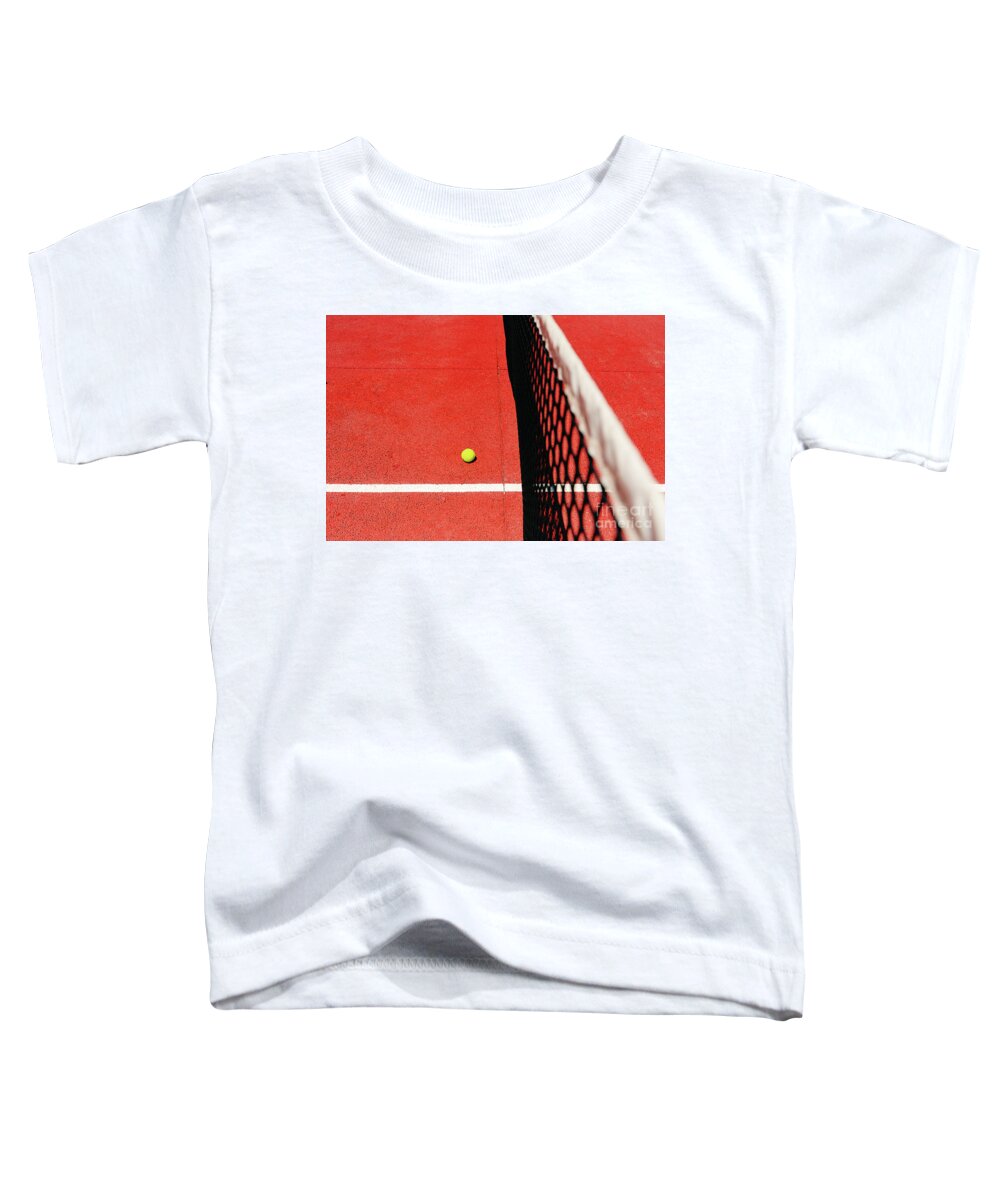 Ace Toddler T-Shirt featuring the photograph A tennis ball on the textured floor of a red court near the net after losing a match point. by Joaquin Corbalan