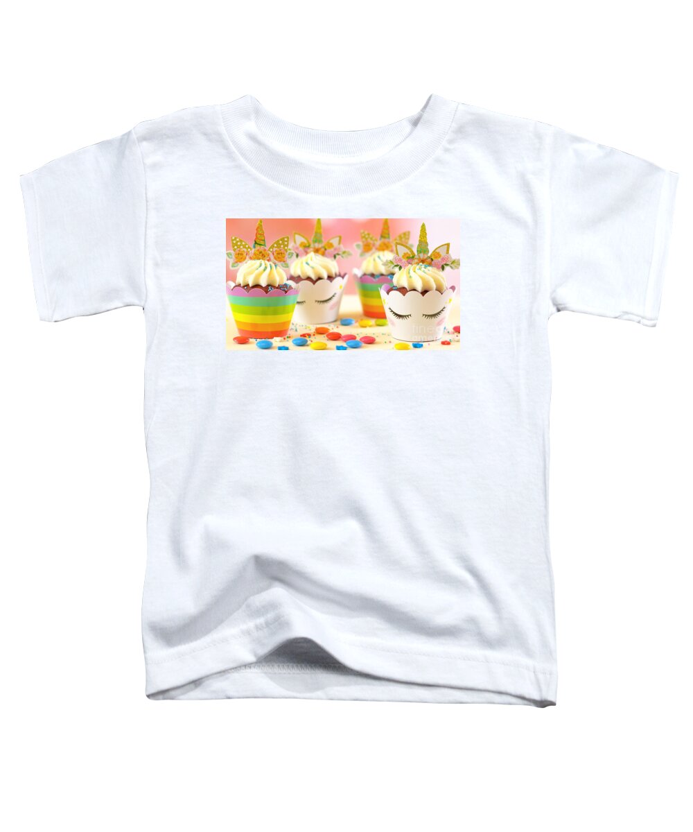 Cupcake Toddler T-Shirt featuring the photograph Decorating children's birthday party unicorn themed cupcakes, closeup. by Milleflore Images