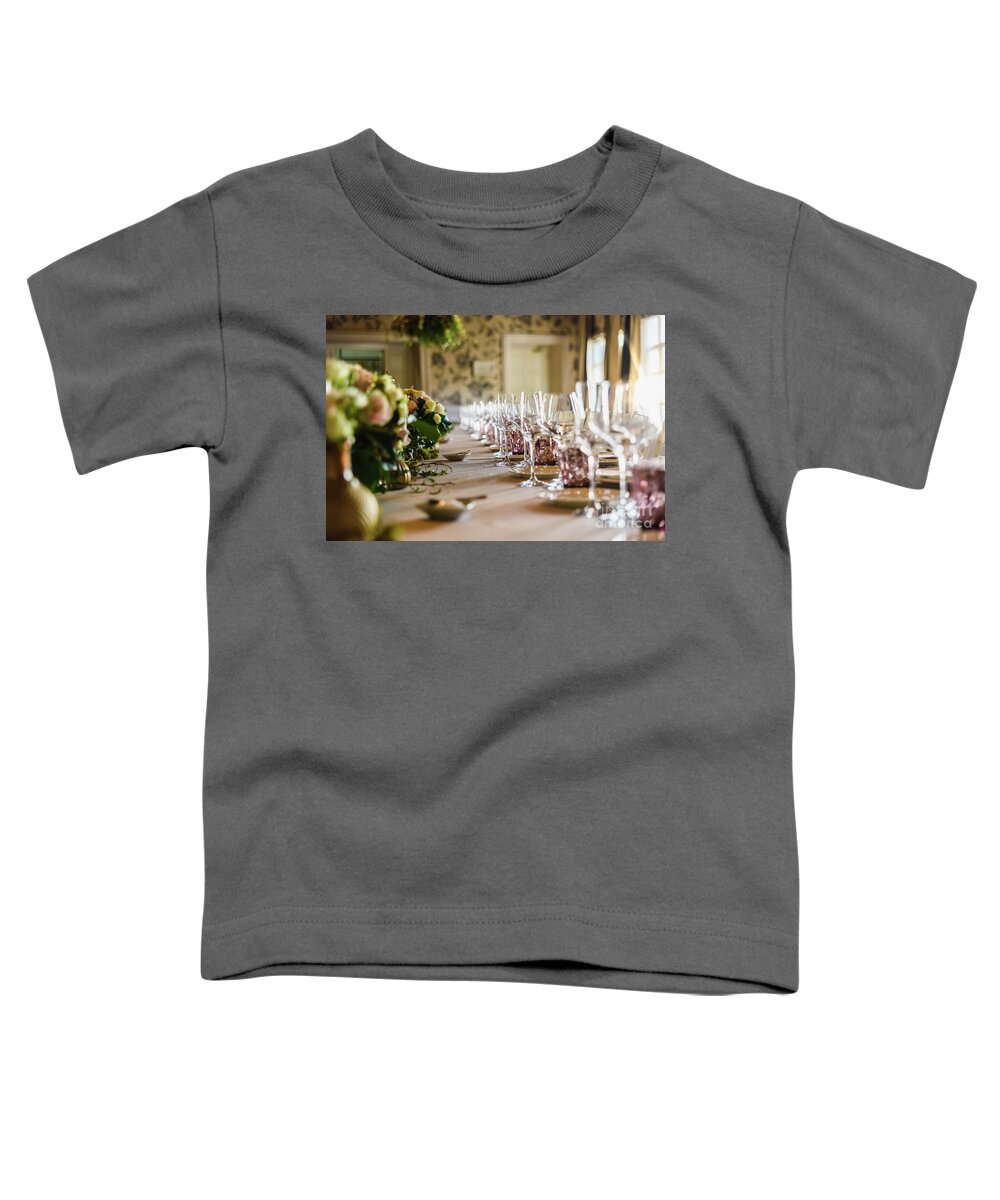 Alcohol Toddler T-Shirt featuring the photograph Elongated table with all the cutlery elegantly arranged and beautiful centerpieces ideal for decorating a wedding. by Joaquin Corbalan