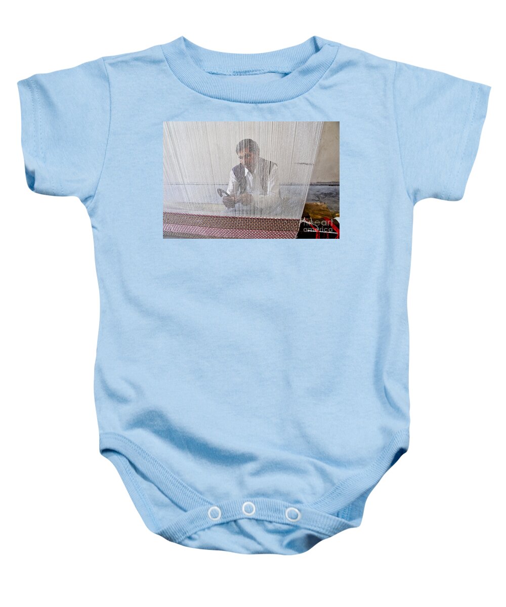Carpet Weaving Baby Onesie featuring the photograph A weaver weaves a carpet. by Elena Perelman