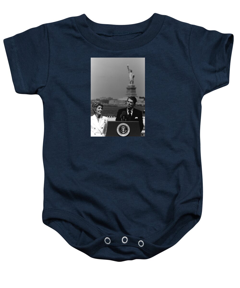 Ronald Reagan Baby Onesie featuring the photograph Reagan Speaking Before The Statue Of Liberty by War Is Hell Store