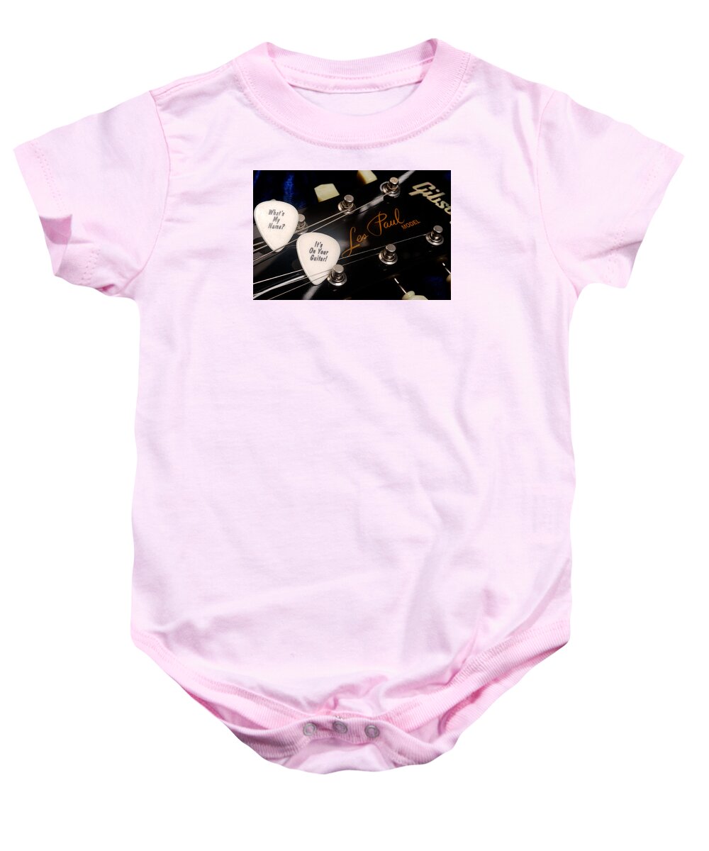 Les Paul Baby Onesie featuring the photograph Les Paul's guitar pick on Gibson headstock by Gene Martin by David Smith