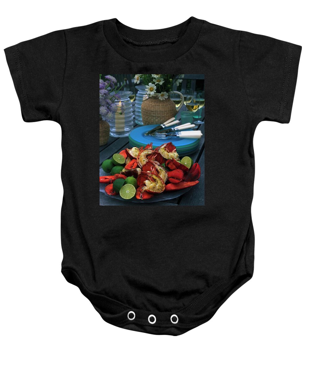 Still Life Baby Onesie featuring the photograph A Meal With Lobster And Limes by Romulo Yanes