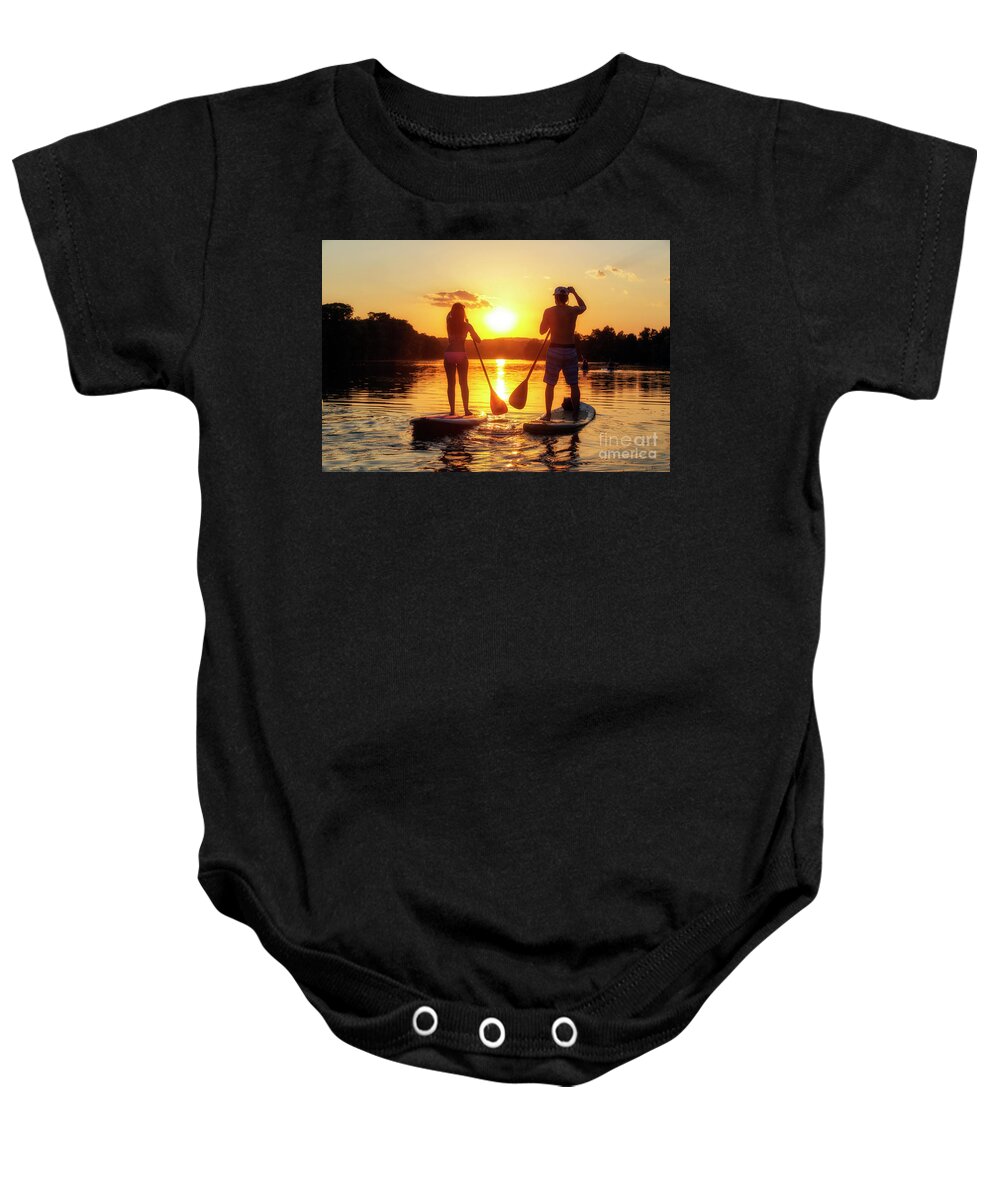 Silhouette Baby Onesie featuring the photograph A silhouette of a couple on a stand-up paddle boards SUP at sunset on Lady Bird Lake in Austin Texas by Dan Herron