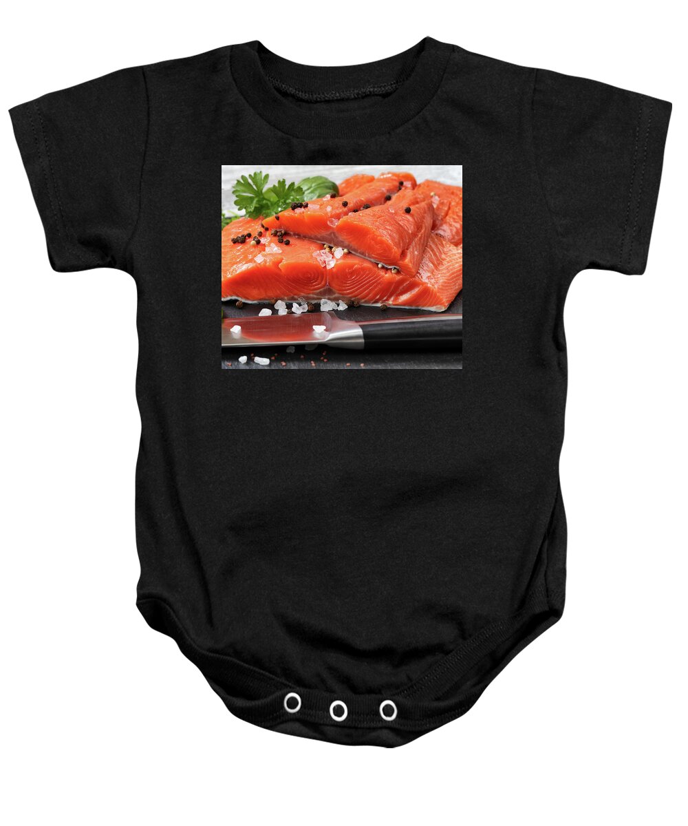 Fresh raw pacific wild king salmon fillets on natural stone with Baby Onesie