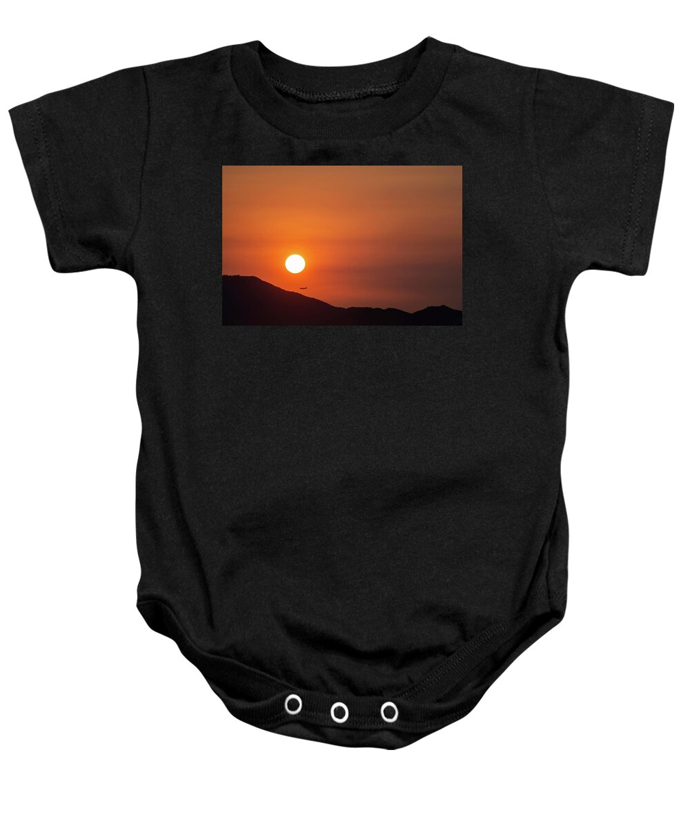 Sunset Baby Onesie featuring the photograph Red sunset and plane in flight by Hannes Roeckel