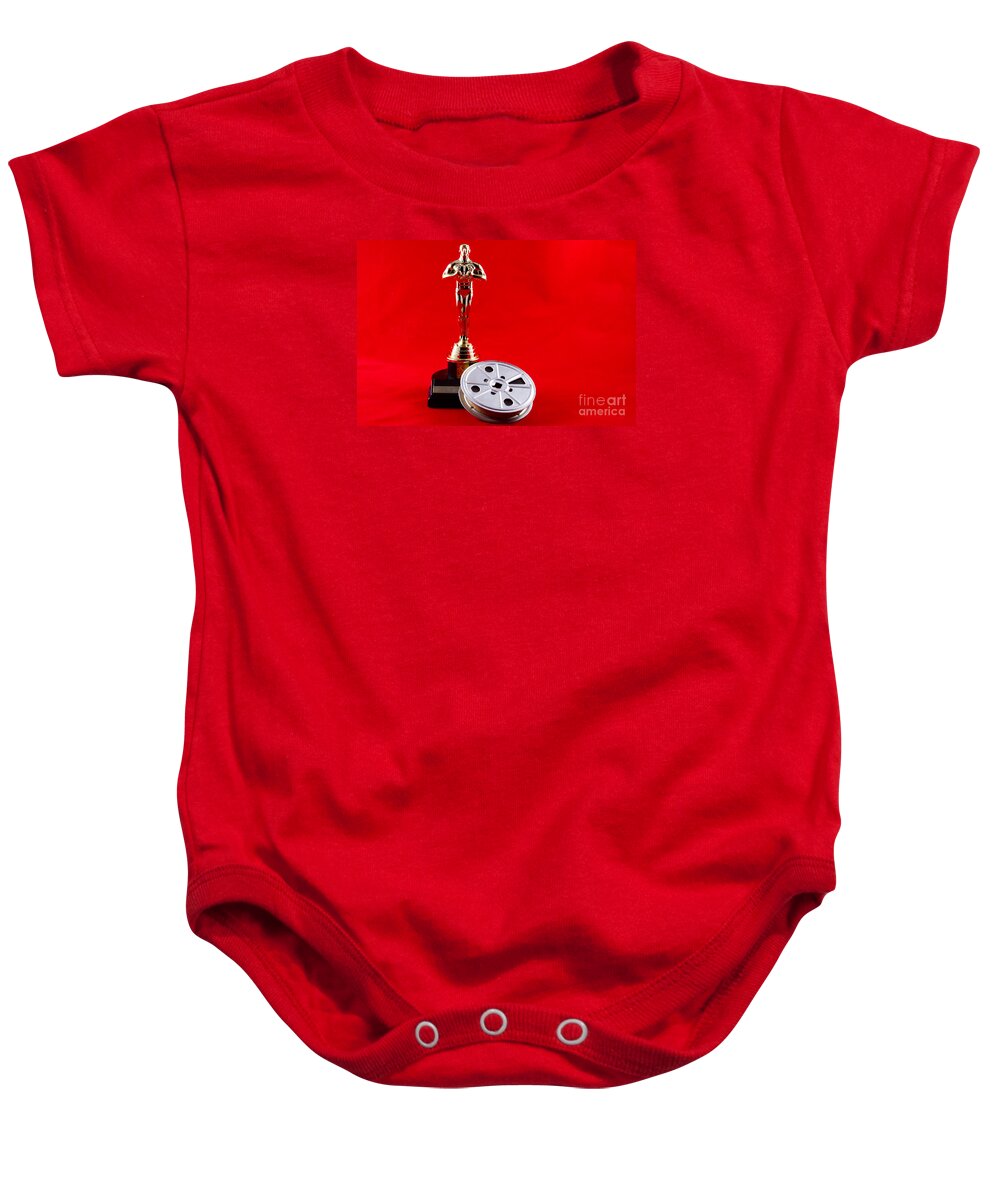 Academy Baby Onesie featuring the photograph Oscar Statuette with Movie Reel by Karen Foley
