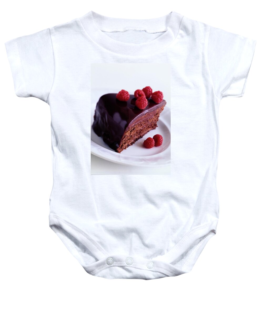 Cooking Baby Onesie featuring the photograph A Chocolate Pecan Cake With Raspberries On Top by Romulo Yanes