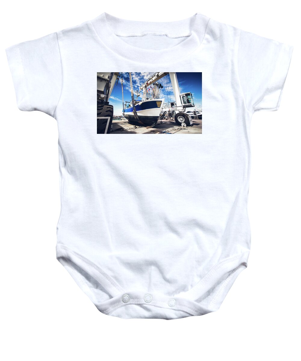 Blue Baby Onesie featuring the photograph Fishing boat lifted by a boat lift by Jean-Luc Farges