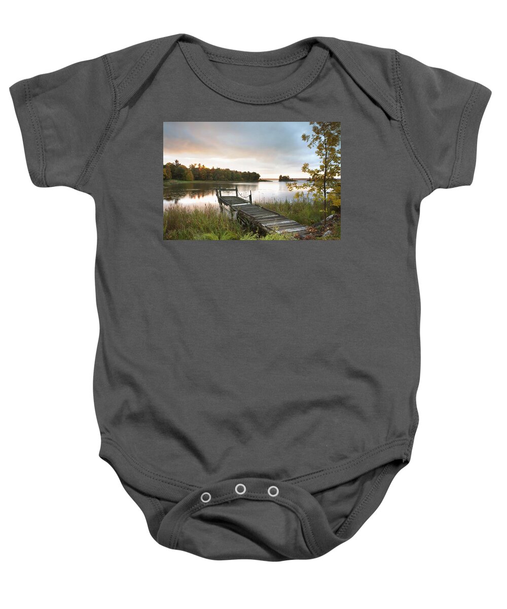 Sunrise Baby Onesie featuring the photograph A Dock On A Lake At Sunrise Near Wawa by Susan Dykstra