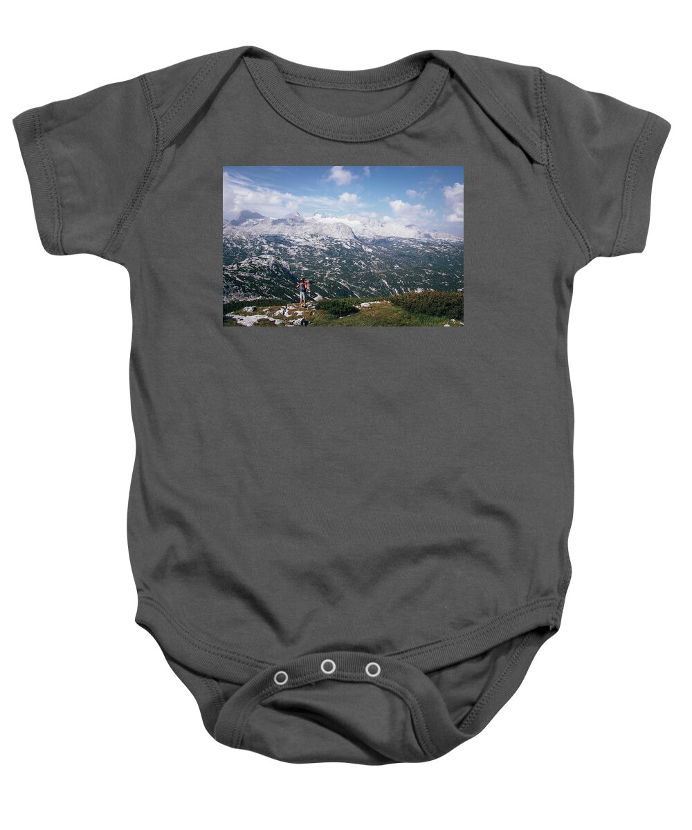 Sportive Baby Onesie featuring the photograph Man with a backpack looks at the Dachstein massif by Vaclav Sonnek