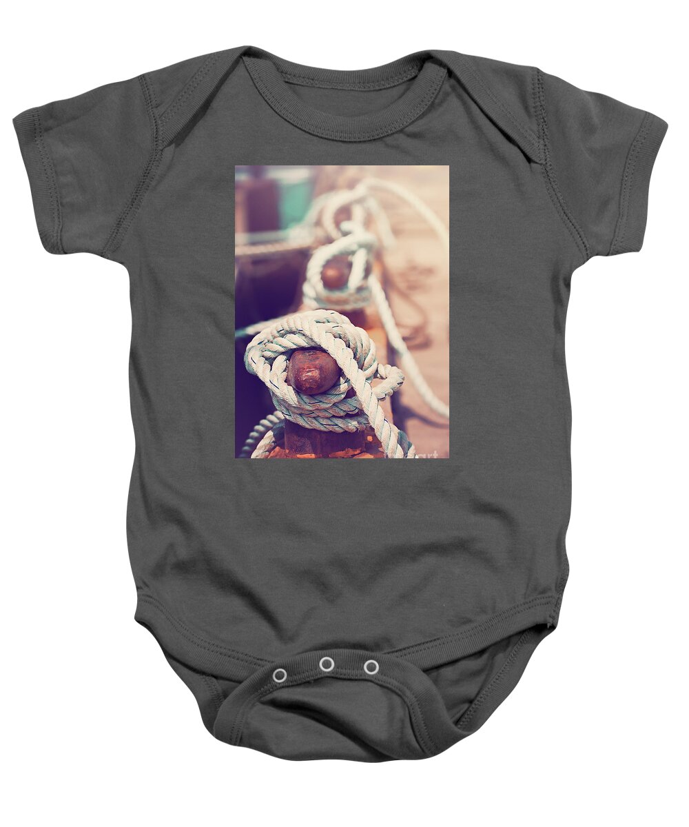 Sea Baby Onesie featuring the photograph Quayside cleats and tied ropes with boats moored in the backgrou by Jane Rix