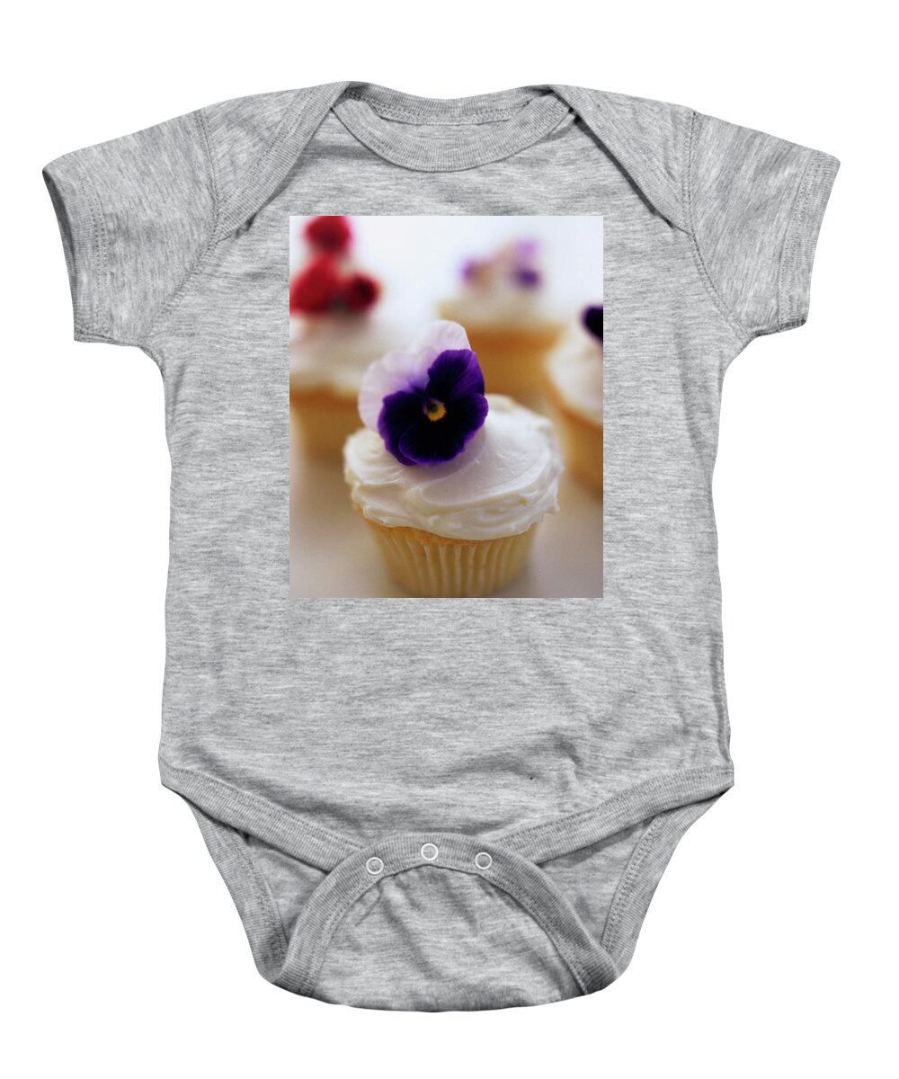 Bridal Baby Onesie featuring the photograph A Cupcake With A Violet On Top by Romulo Yanes