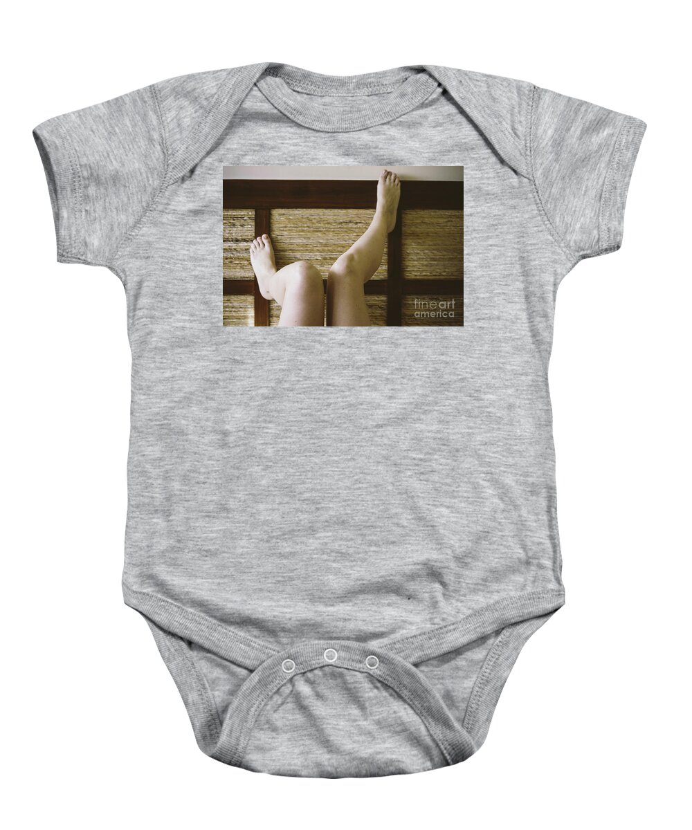 Adult Baby Onesie featuring the photograph Bare feet of woman leaning on the headboard of her bed in a sexy way. by Joaquin Corbalan