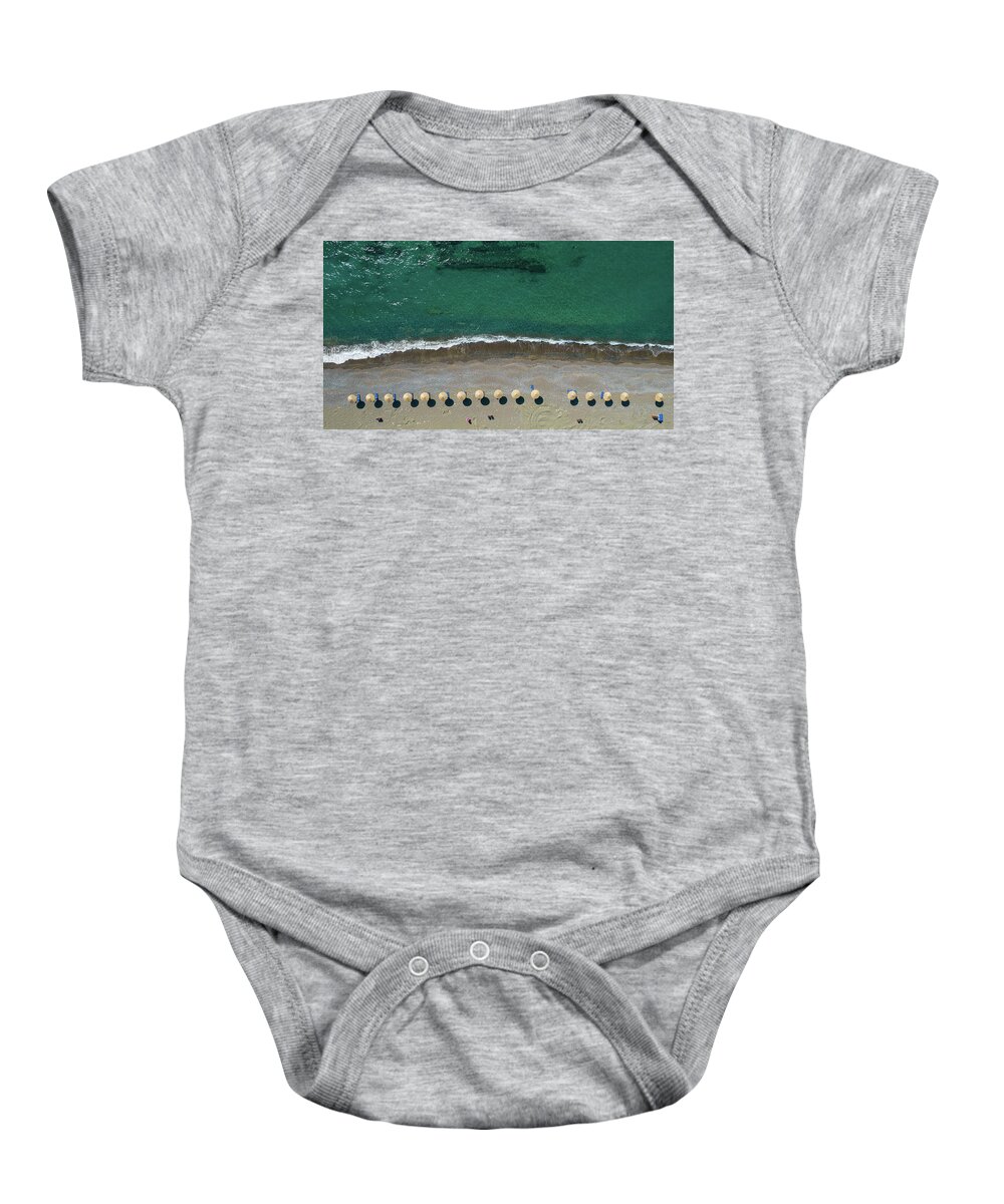 Summertime Baby Onesie featuring the photograph Aerial view from a flying drone of beach umbrellas in a row on an empty beach with braking waves. #1 by Michalakis Ppalis