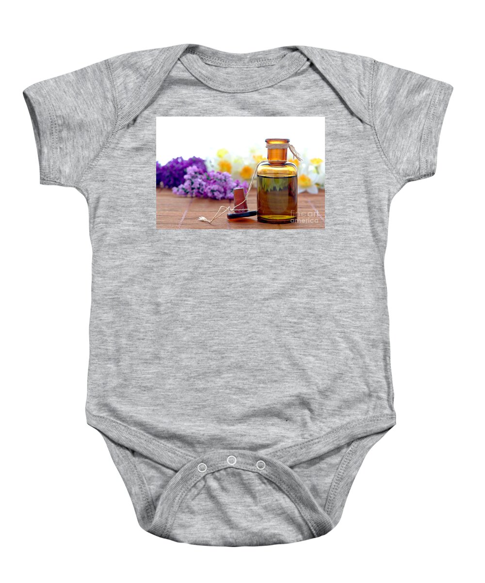Amber Baby Onesie featuring the photograph Aromatherapy Essential Oil Bottle with Flowers in a Spa by Olivier Le Queinec