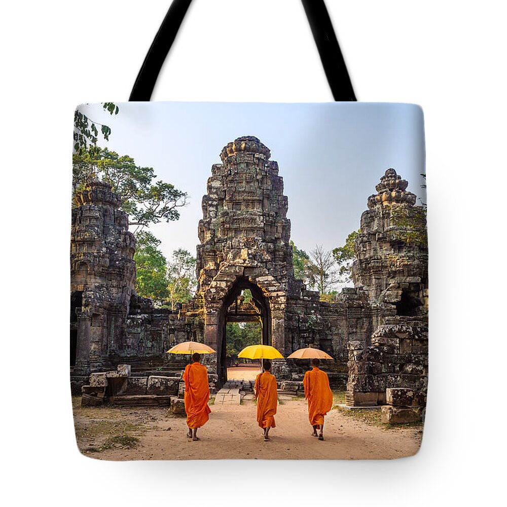 Angkor Tote Bag featuring the photograph Monks with umbrella walking into Angkor Wat temple - Cambodia #1 by Matteo Colombo