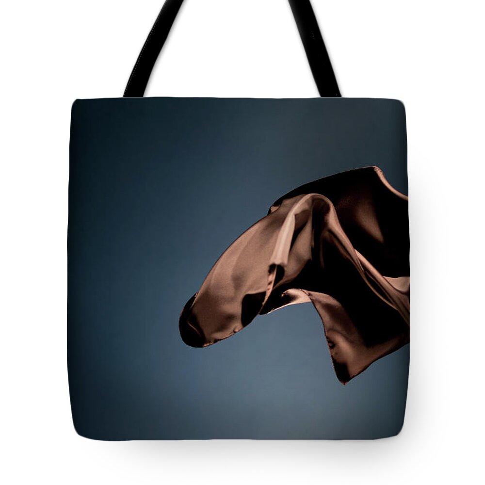 Black Background Tote Bag featuring the photograph Floating Brown Satin On A Dark Blue #3 by Gm Stock Films