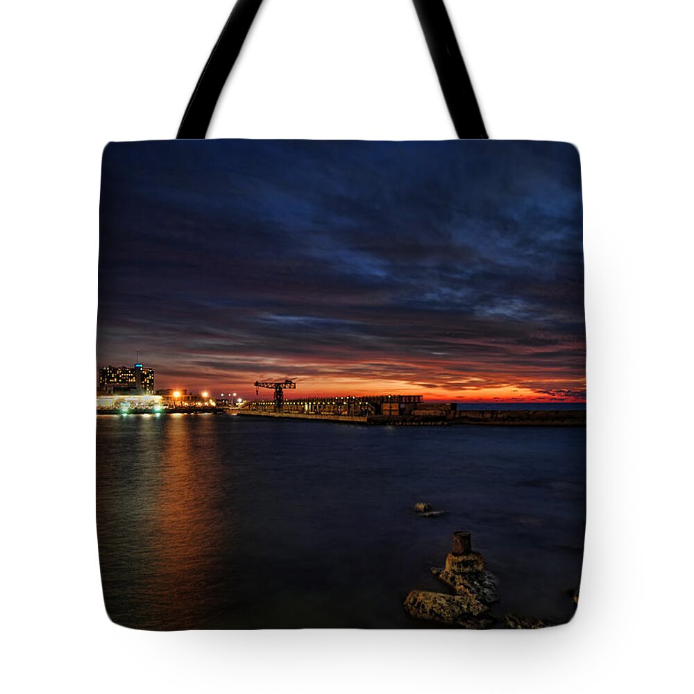Israel Tote Bag featuring the photograph a flaming sunset at Tel Aviv port by Ron Shoshani
