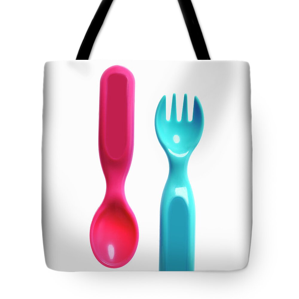 Material Tote Bag featuring the photograph A Pink Plastic Baby Spoon And A Blue by Mint Images - David Arky