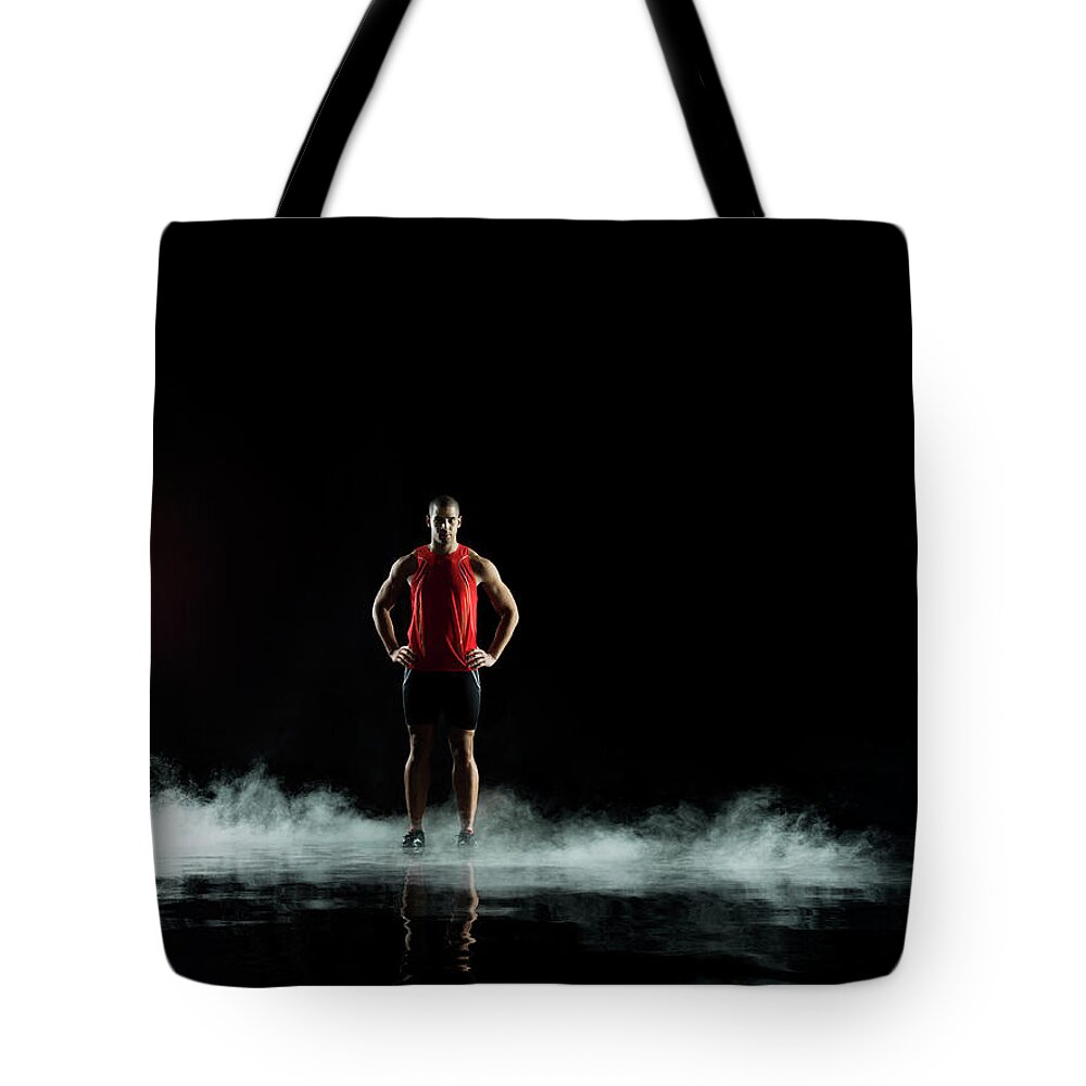 Toughness Tote Bag featuring the photograph Athelete Standing In Water At Night by Jonathan Knowles