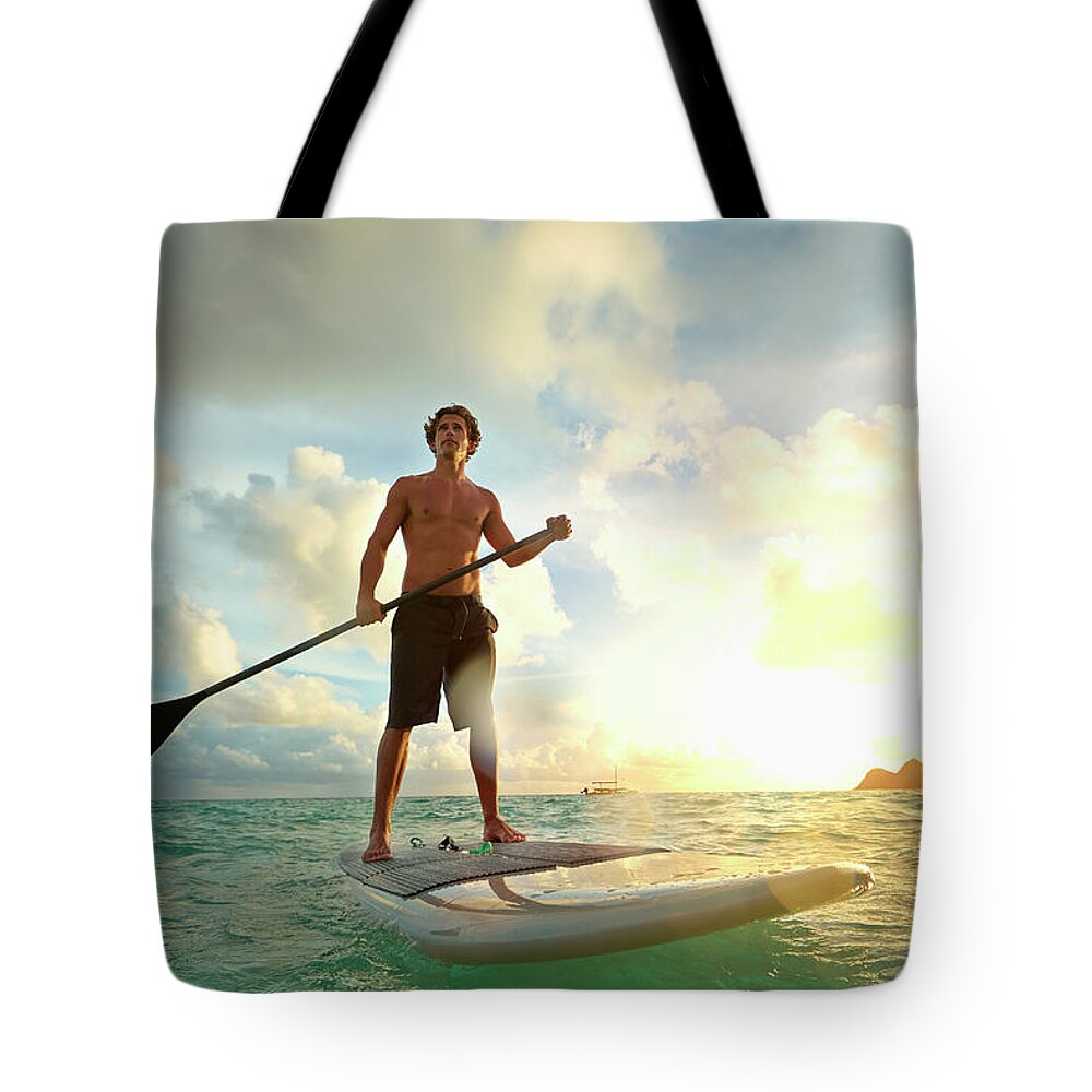 Tranquility Tote Bag featuring the photograph Caucasian Man On Paddle Board In Water by Colin Anderson Productions Pty Ltd
