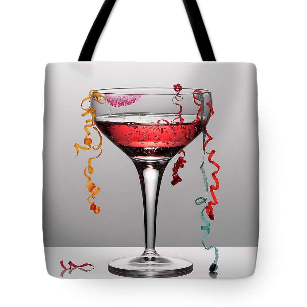 Streamer Tote Bag featuring the photograph Confetti Hanging From Glass Of Pink by Andy Roberts