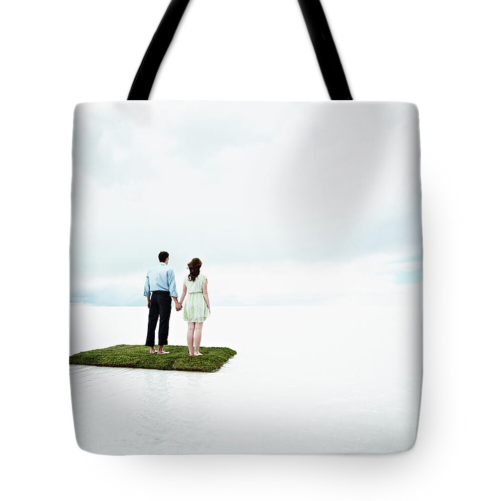 Young Men Tote Bag featuring the photograph Couple On Small Island In Large Body Of by Thomas Barwick