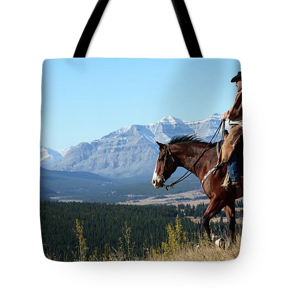 Cowboy Tote Bag featuring the photograph Cowboy Riding With A View Of The Rocky by Deb Garside