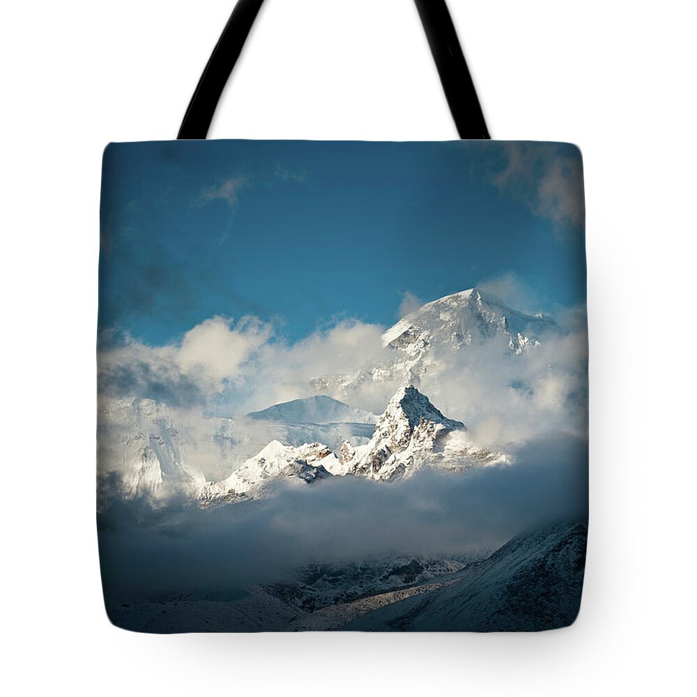 Himalayas Tote Bag featuring the photograph Dramatic Clouds Swirling Around Snowy by Fotovoyager