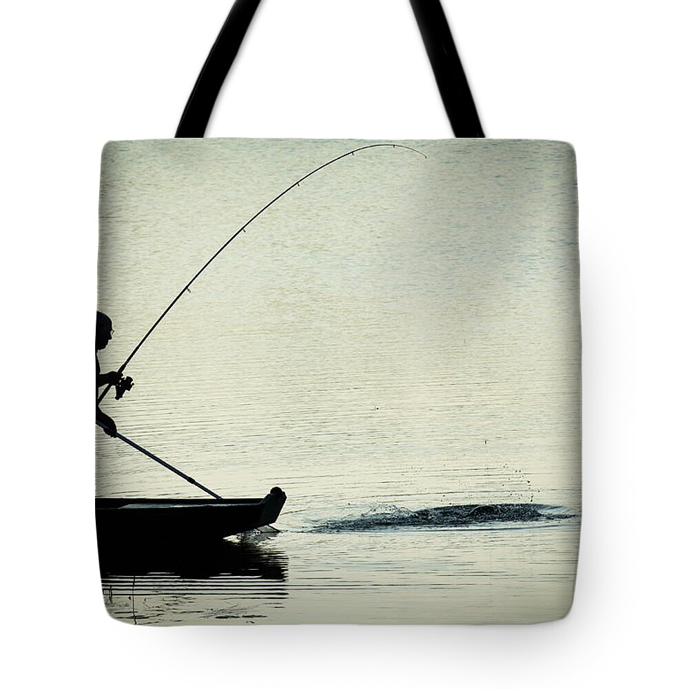 Fisher Tote Bag featuring the photograph Fisherman Catching Fish On A Twilight Lake by Andreas Berthold