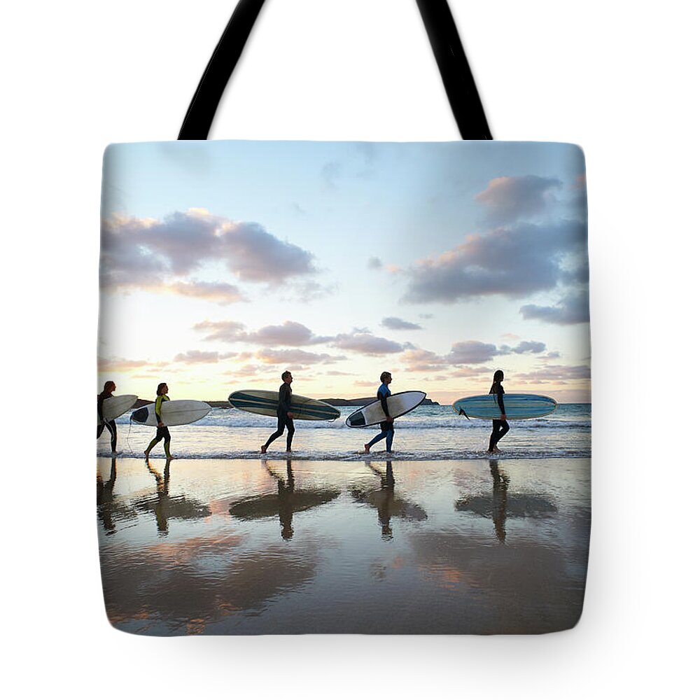 Young Men Tote Bag featuring the photograph Five Surfers Walk Along Beach With Surf by Dougal Waters