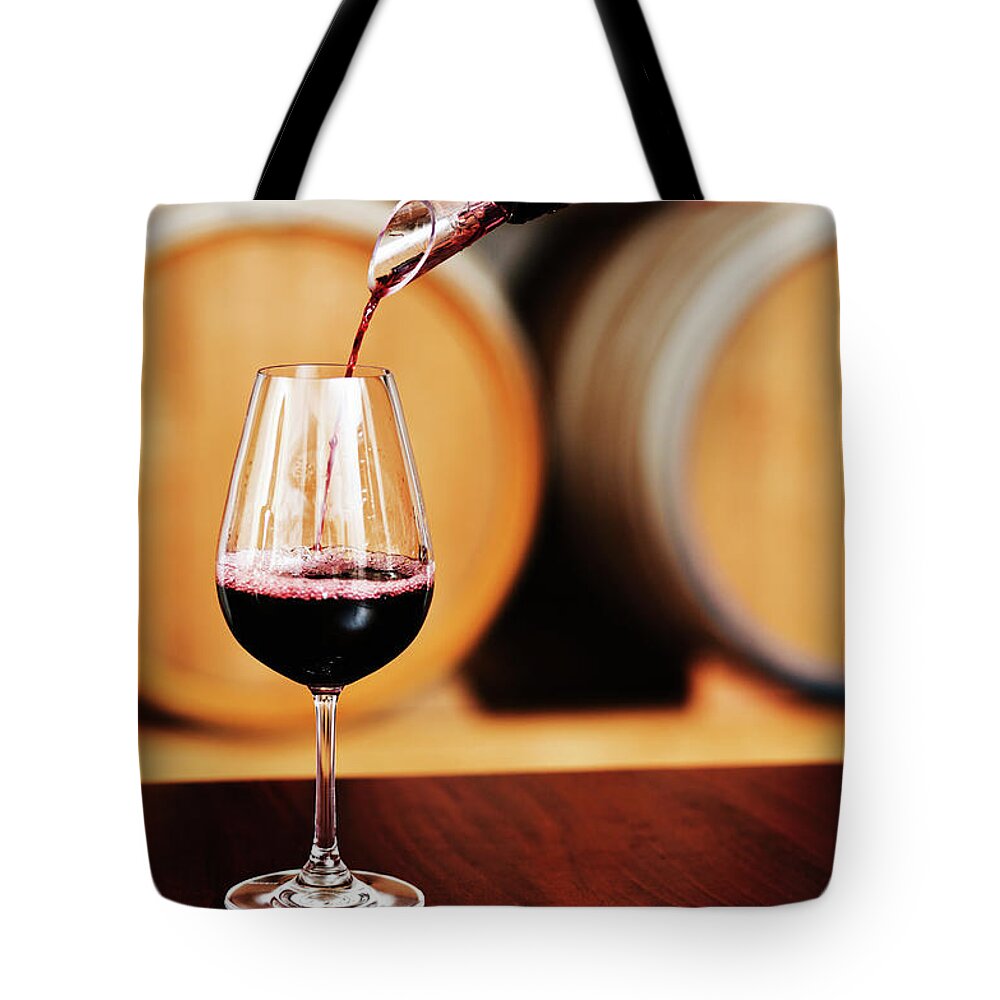 Alcohol Tote Bag featuring the photograph Glass Of Red Wine Being Poured At by Rapideye