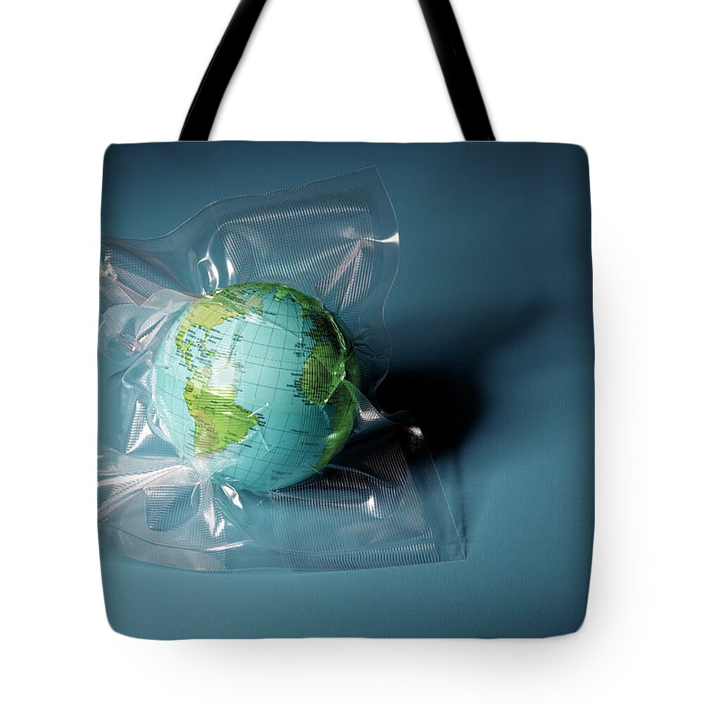 Environmental Conservation Tote Bag featuring the photograph Globe Shrink Wrapped In Plastic by Henrik Weis