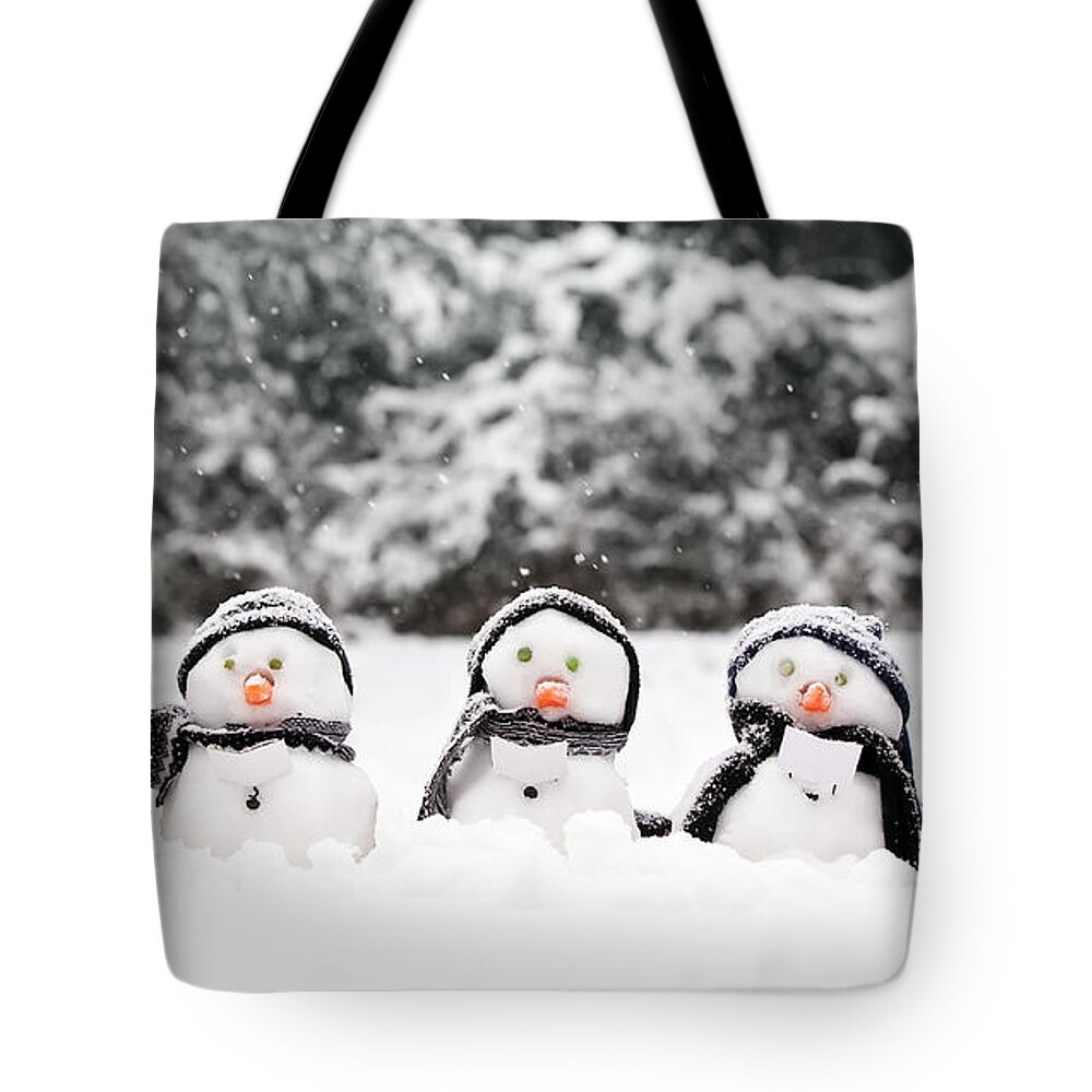 Snowmen Tote Bag featuring the photograph Little snowmen in a group by Simon Bratt