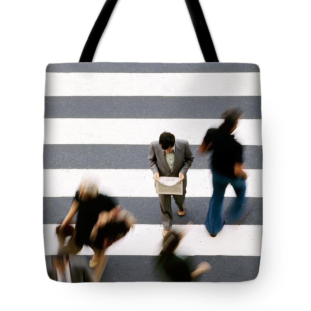 Zebra Crossing Tote Bag featuring the photograph Man walking and reading newspaper on zebra crossing by Juan Carlos Ferro Duque