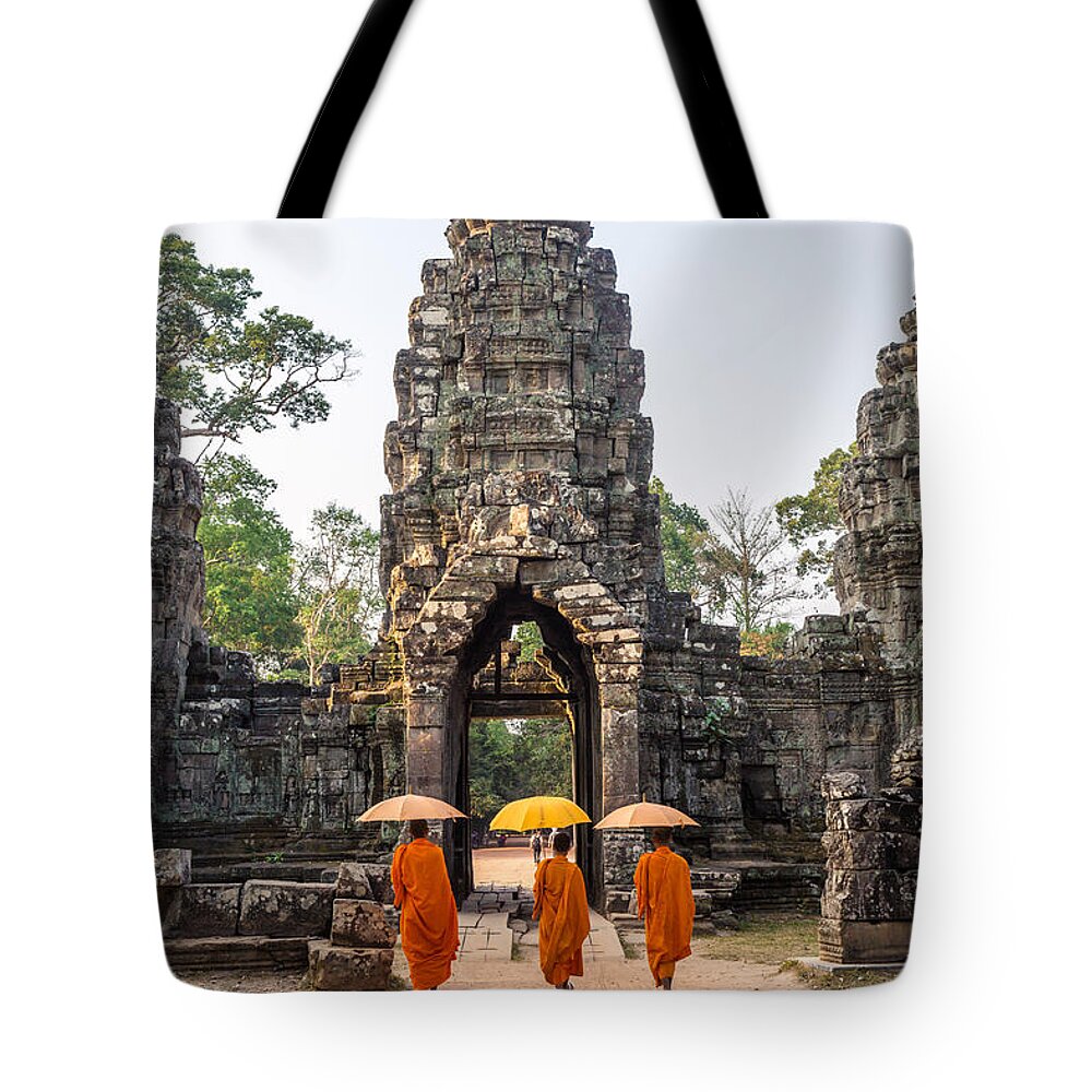 Angkor Tote Bag featuring the photograph Monks with umbrella walking into Angkor Wat temple - Cambodia by Matteo Colombo