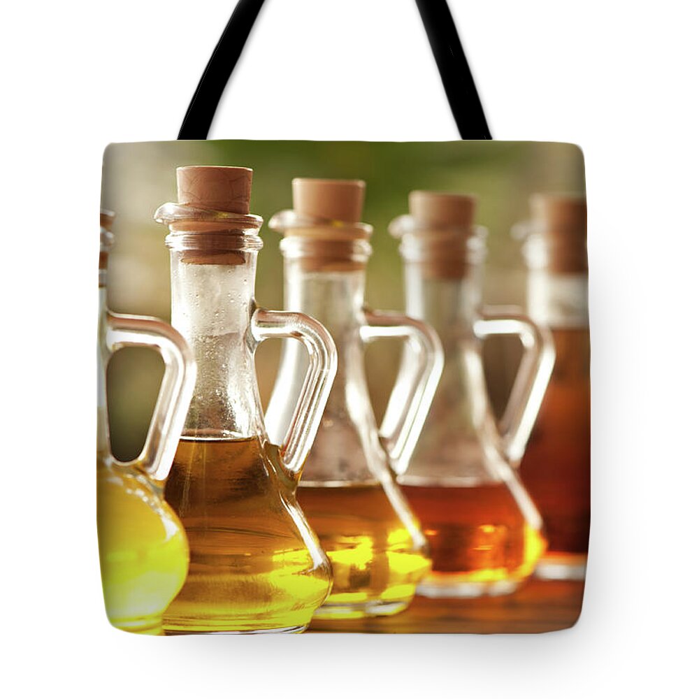 In A Row Tote Bag featuring the photograph Olive Oil And Vinegar In Bottles On The by Ralucahphotography.ro