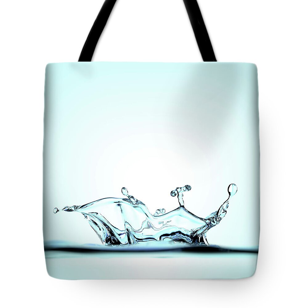 Motion Tote Bag featuring the photograph Splash Of Water Against A Blue by Atomic Imagery