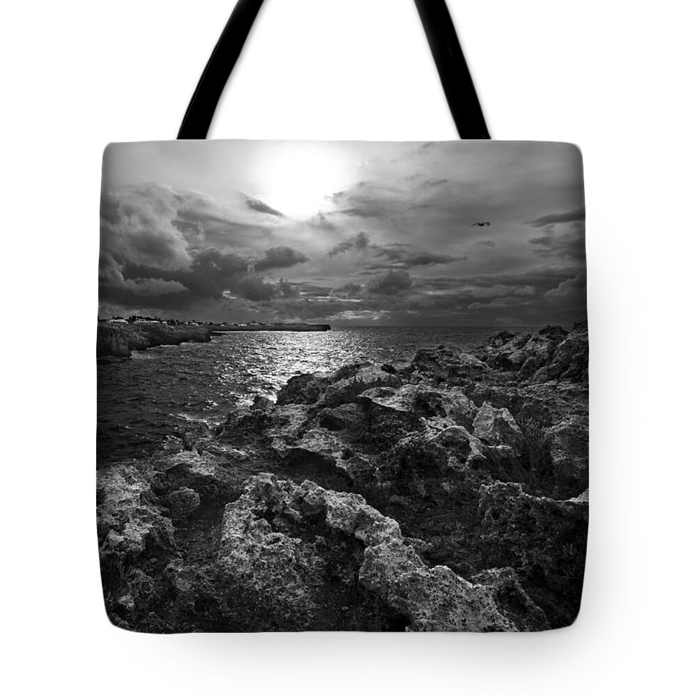 Background Tote Bag featuring the photograph Blank and white stormy mediterranean sunrise in contrast with black rocks and cliffs in Menorca by Pedro Cardona Llambias