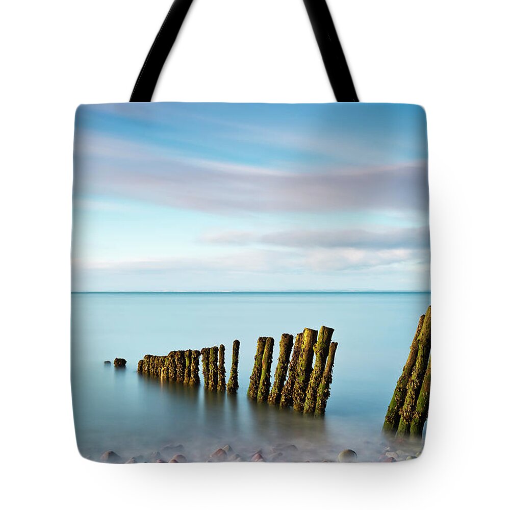 Scenics Tote Bag featuring the photograph Wooden Groynes On A Beach At Low Tide by Jeremy Walker