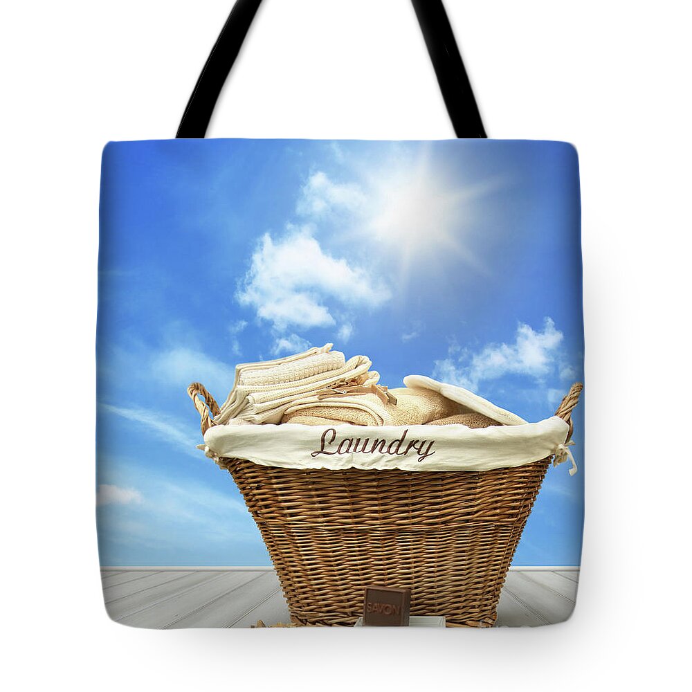 Cleaning Tote Bag featuring the photograph Laundry basket with clothes on rustic table against blue sky #1 by Sandra Cunningham