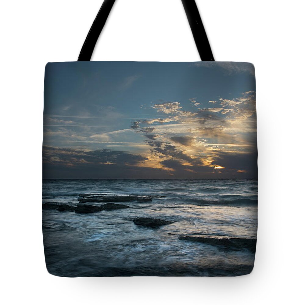 Sunset Over Sea Tote Bag featuring the photograph Sunset on a rocky beach by Michalakis Ppalis