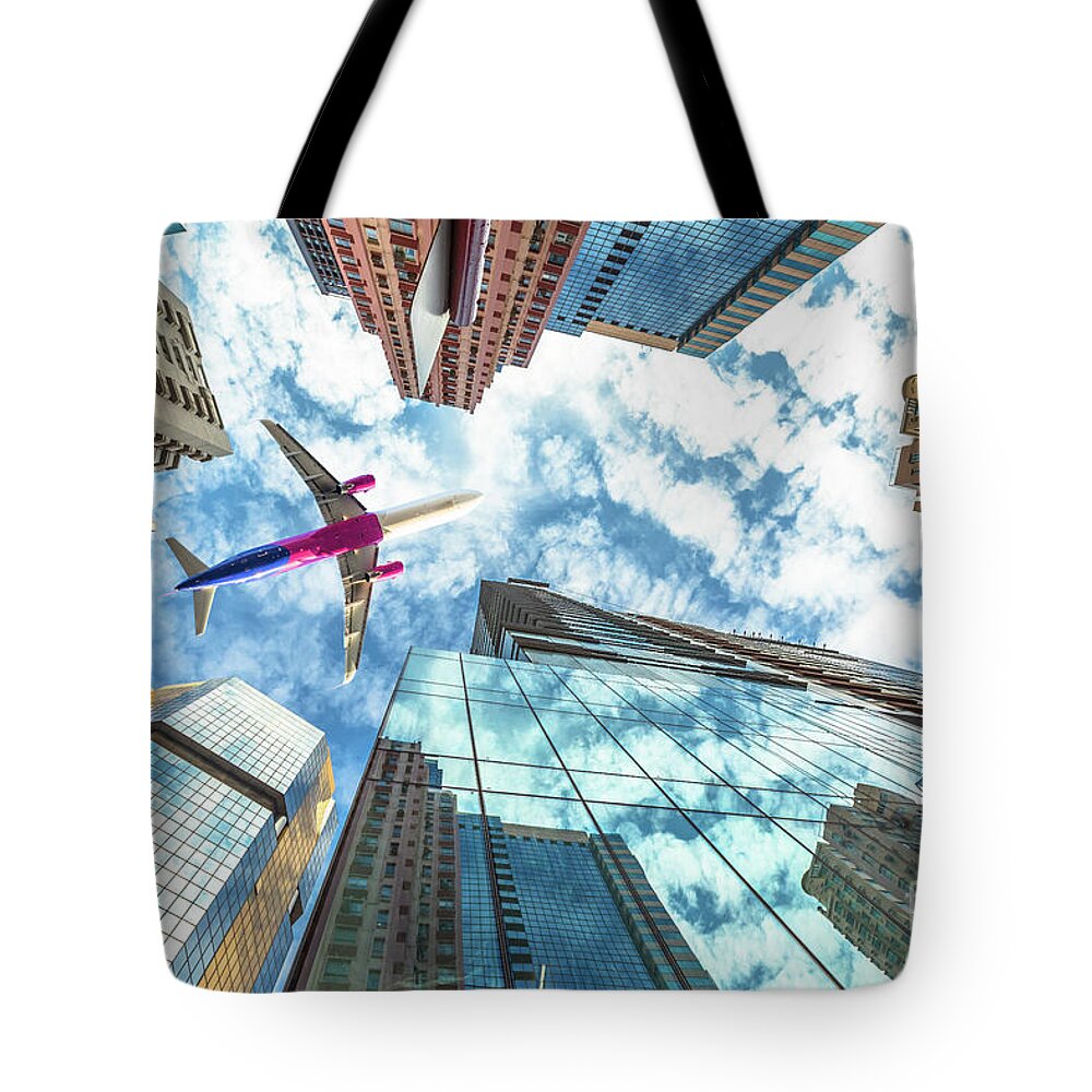 Hong Kong Tote Bag featuring the photograph Airplane flying over skyscrapers by Benny Marty